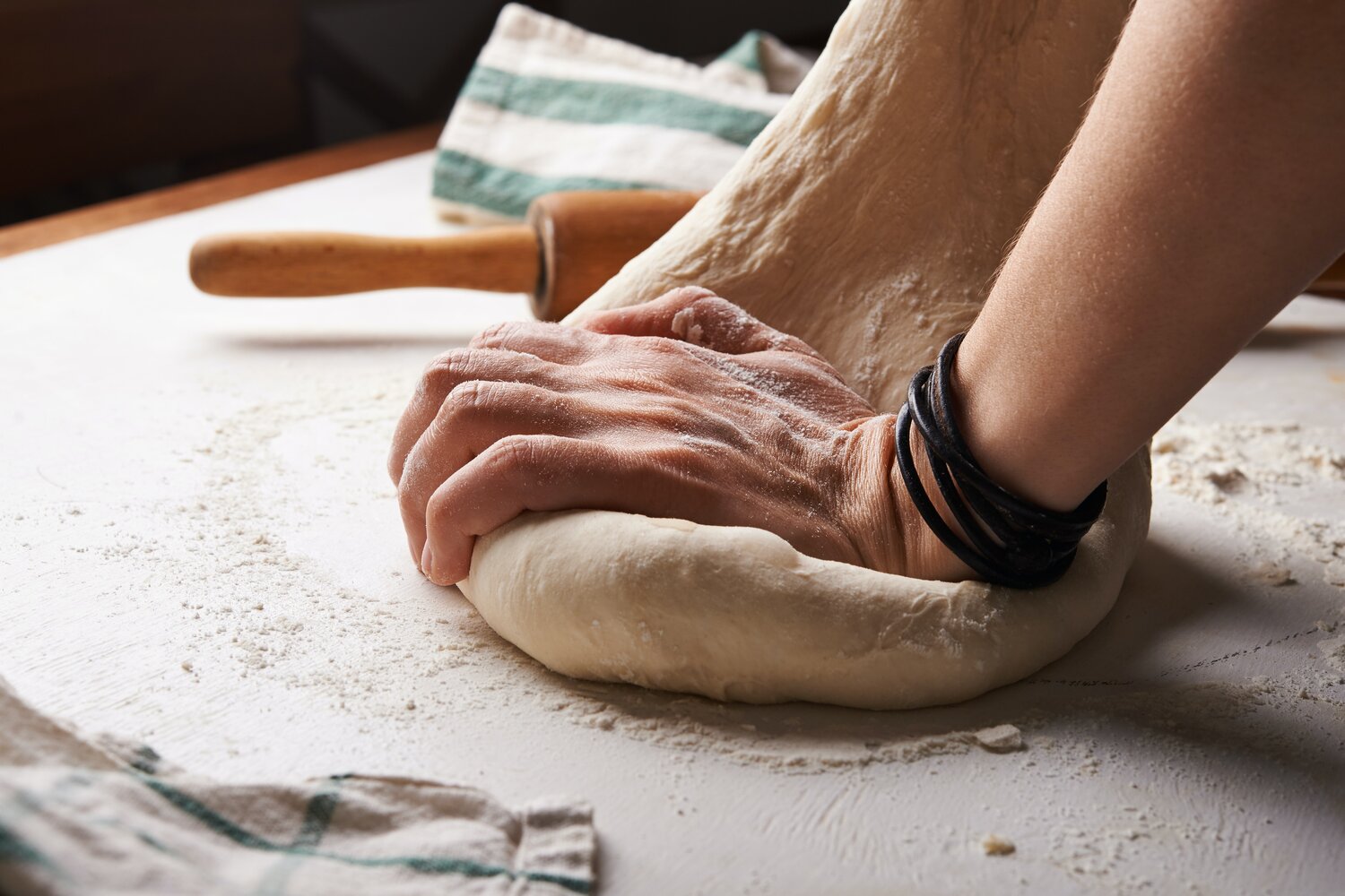 Handen die verse pasta kneden op een met bloem bestoven werkblad