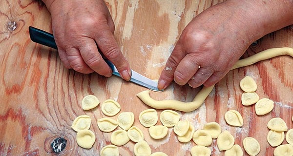 Orecchiette die met een mes met de hand worden gevormd op een houten plank
